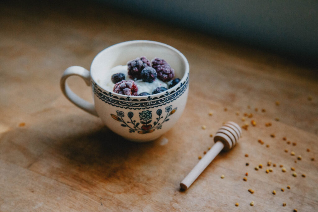 A teacup full of creamy goat milk yogurt and berries.