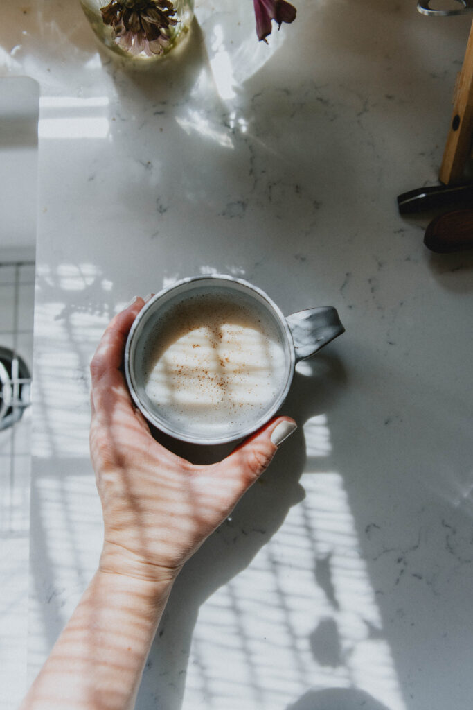 Spicy mushroom chai fills a handmade ceramic mug atop a marble countertop.